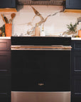 Brass and copper appliance handle installed on a Whirlpool range oven in a modern kitchen.