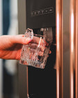 Person getting a drink from a Whirlpool stainless steel side by side refrigerator that displays an interchangeable appliance handle for stainless steel appliances