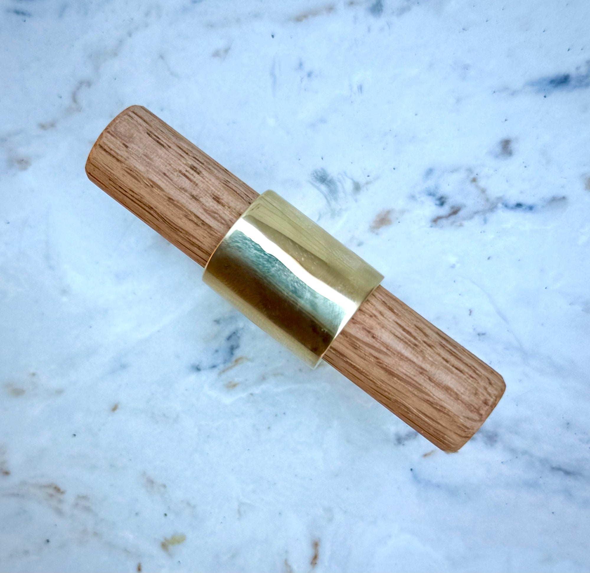 Luxury brass T-knob with solid oak handle displayed on cabinet door.