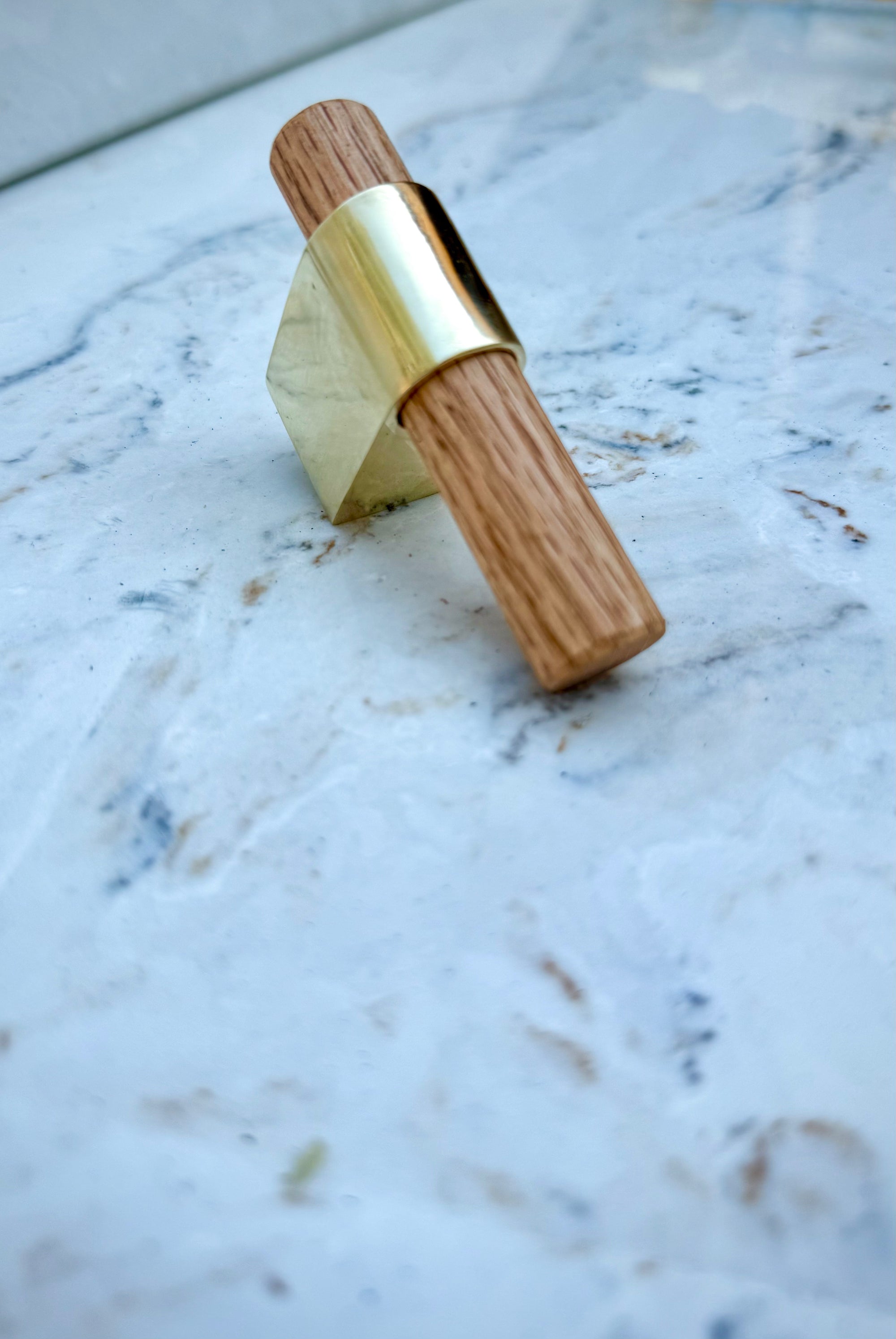 Luxury brass T-knob with solid oak handle displayed on cabinet door.
