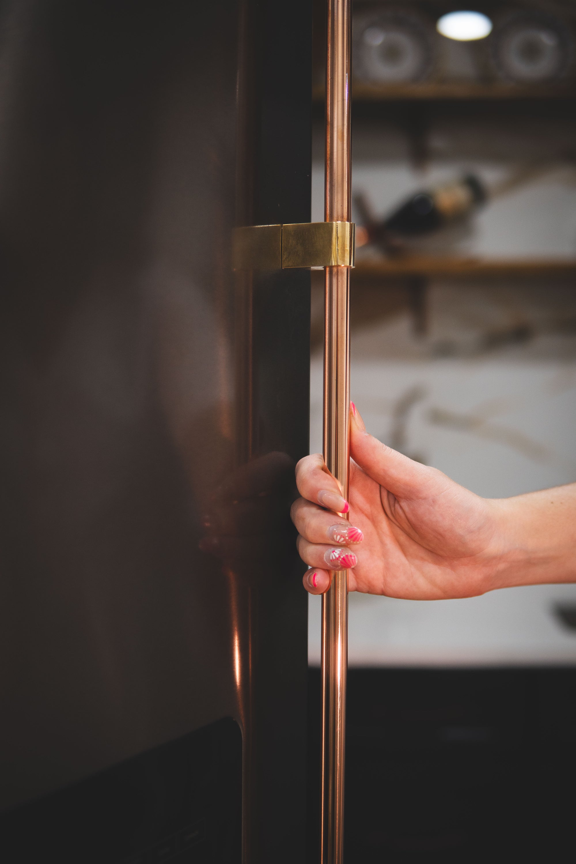 Person opening a copper and brass whirlpool side by side refrigerator door handle